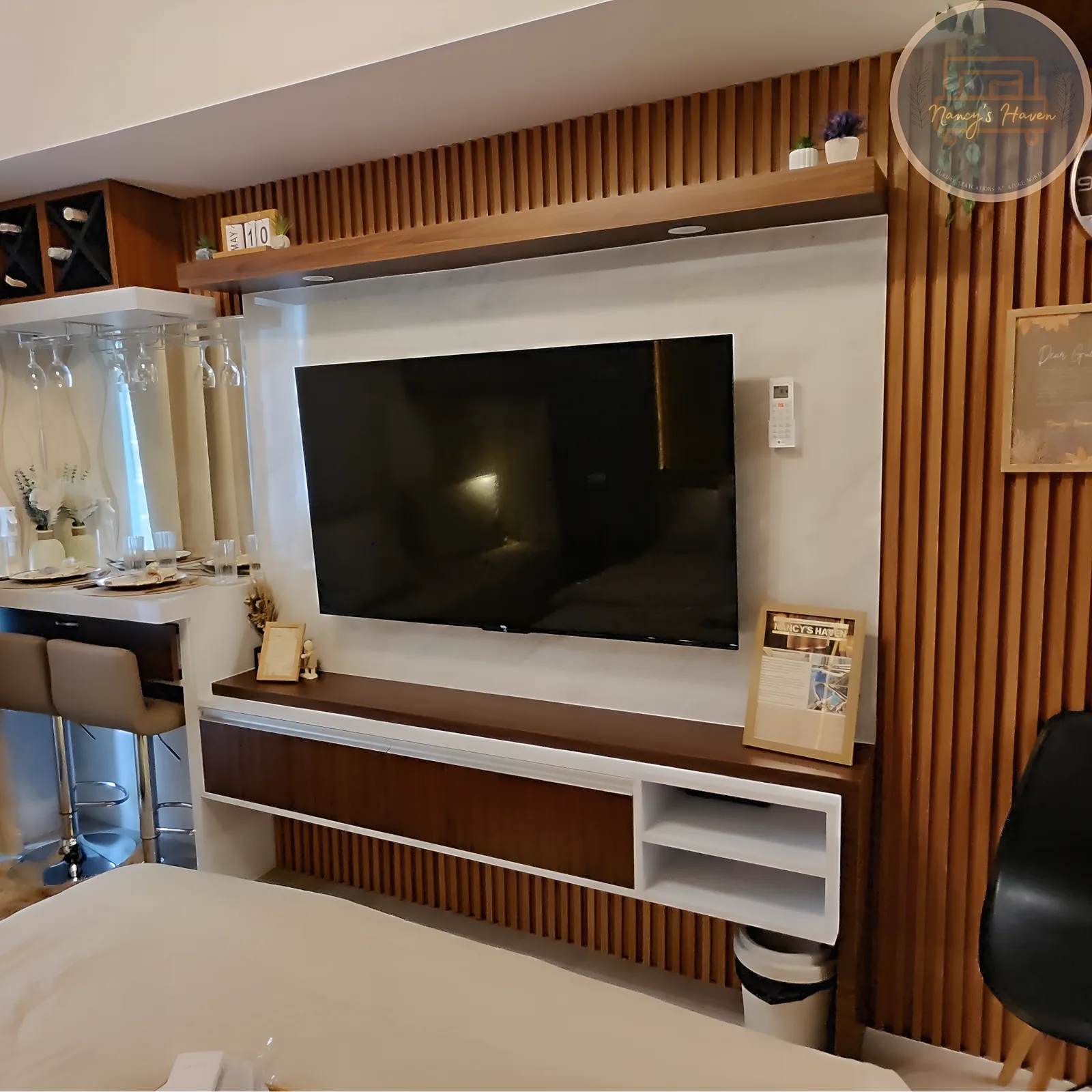 The living space — wood-slat media wall with smart TV and mini-bar counter